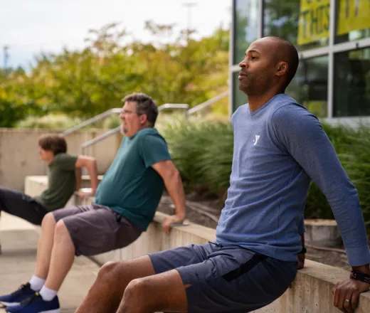 Three men workout outside while practicing safe social distancing